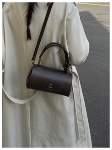 Outdoor shot of a vintage dark brown barrel bag with gold twist-lock and fine leather texture