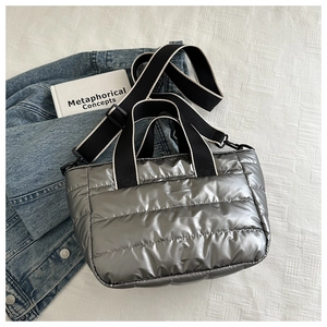 Macro detail of silver quilted puffer bag with contrast webbing strap and metallic finish