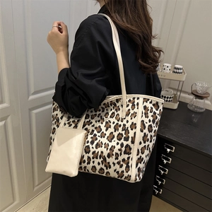 Leopard print tote bag with cream straps and matching pouch shown on a shoulder