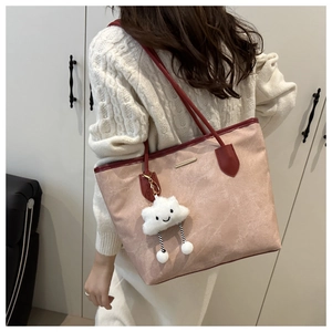 Détail d'un sac cabas rose avec bordure rouge et breloque nuage blanc en décor réel