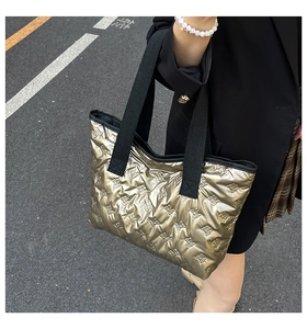 Detailed close-up of a quilted gold metallic tote bag with chic bow pattern and wide straps