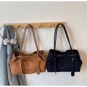 Detail view of suede underarm bags in brown and black with decorative strap buckles