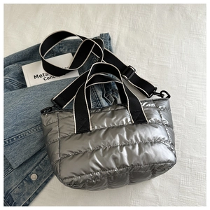 Close-up of silver quilted tote bag with horizontal padding and black handles