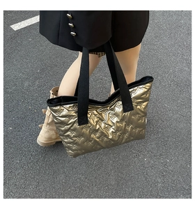 Detail of gold textured tote bag with bow pattern and contrasting black canvas strap