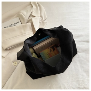 Detail of black suede tote bag showing magnetic snap closure and spacious interior storage