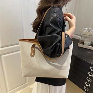 Minimalist cream canvas tote bag with brown leather straps shown on a model for daily commute