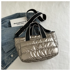 Close-up of quilted silver puffer tote bag with black and white strap and denim jacket