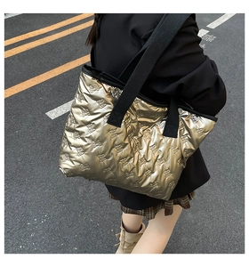 Detail of gold quilted tote bag with bow texture and black textile straps