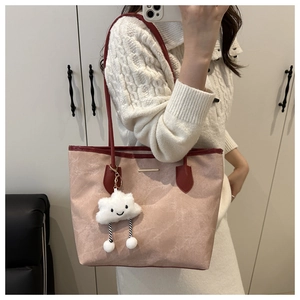Détail d'un sac cabas rose clair avec anses rouge foncé et un charm nuage en peluche