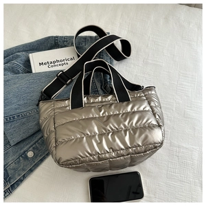 Detail of silver metallic quilted tote bag with padded texture and woven strap in lifestyle setting