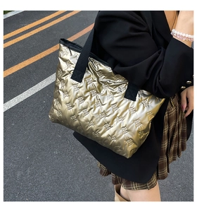 Golden metallic quilted tote bag with bow patterns held by model in street style shot