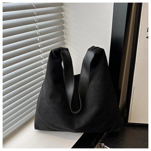 Close-up of minimalist black matte tote bag with wide shoulder strap in modern interior