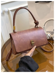 Close-up of vintage brown leather handbag with gold twist lock and braided handle
