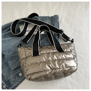 Close-up of metallic silver quilted tote bag with wide woven handles and puffy texture