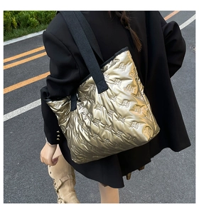Detail of champagne gold puffer tote bag with quilted bow texture and black strap
