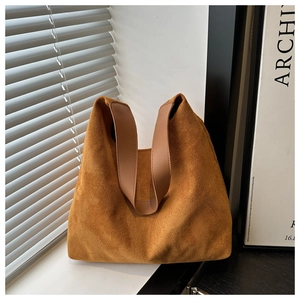 Close-up of brown suede hobo bag with leather strap in soft natural sunlight