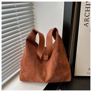 Brown suede tote bag detail featuring smooth wide leather handle and minimalist design