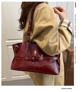 Detail view of burgundy leather shoulder bag with decorative metallic eyelet buckle straps