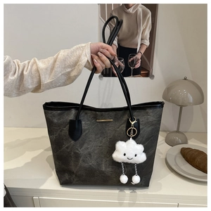 Close-up of charcoal gray textured tote bag with golden hardware and plush cloud charm