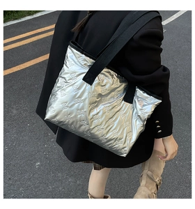 Close-up of silver puffy tote bag featuring textured butterfly embossed patterns and black strap