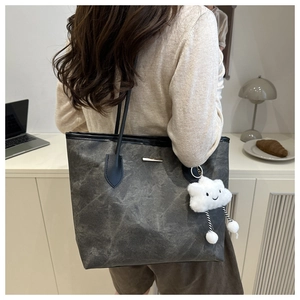 Detail of grey textured canvas tote bag with a cute white cloud plush charm accessory
