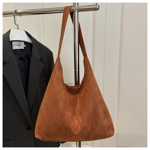 Detail of a brown suede hobo tote bag hanging on a metal rack with minimalist design