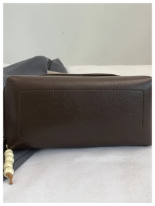 Dettaglio della borsa in pelle marrone con cuciture e perline di legno decorative