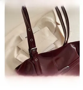 Close-up of deep red tote bag with silver eyelets and high-gloss leather texture