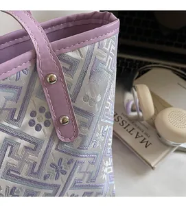 Detail of purple woven tote bag with silver rivets and floral textured fabric pattern