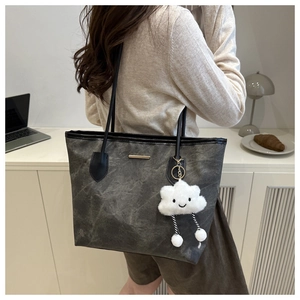 Detail of dark grey tote bag with marble texture and plush cloud pendant accessory
