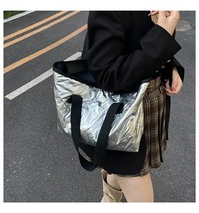 Detailed view of silver metallic padded tote bag with embossed patterns and black wide straps