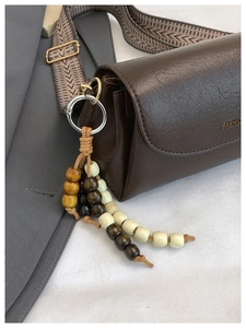 Dettaglio borsa a bauletto in pelle marrone scuro con tracolla jacquard e nappa di perline