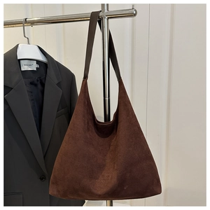 Detail of dark brown suede tote bag with leather strap hanging on a metal rack