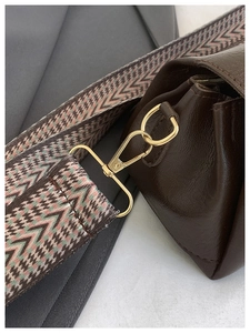 Dettaglio della borsa in pelle marrone con ampia tracolla con motivi colorati