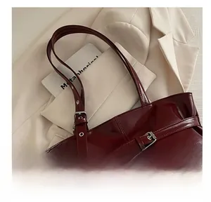 Close-up of a burgundy PU leather tote bag with decorative buckle and strap details