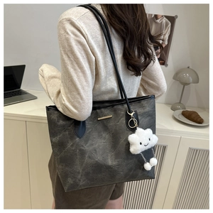 Détail du sac cabas gris foncé texturé avec un joli pendentif en forme de nuage blanc
