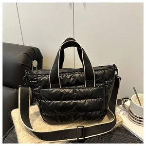 Detail of black quilted puffer tote bag with contrasting cream edge shoulder straps