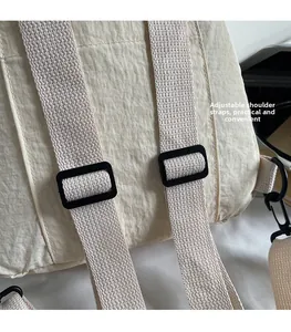Detail of adjustable shoulder straps on a beige nylon backpack with matte plastic buckles