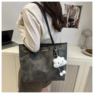 Detail view of large charcoal grey tote bag with soft plush charm and slim shoulder straps
