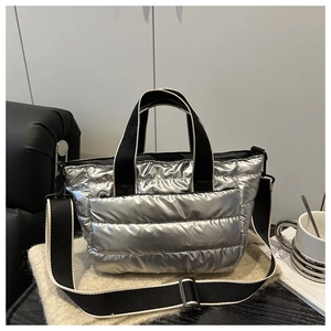 Quilted silver metallic tote bag with woven handles on a modern leather sofa setting