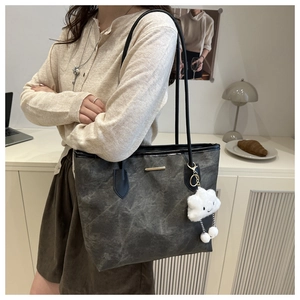 Détail d'un sac cabas gris texturé avec poignées noires et charm nuage en peluche