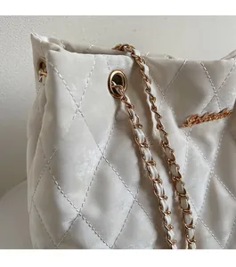 Détail de la texture cuir matelassé et chaîne dorée sur ce sac bandoulière beige