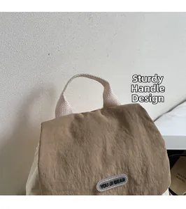 Close-up of khaki nylon backpack featuring durable top handle and brand logo tag detail