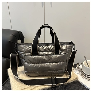 Detail of silver quilted tote bag featuring contrast straps and adjustable shoulder belt