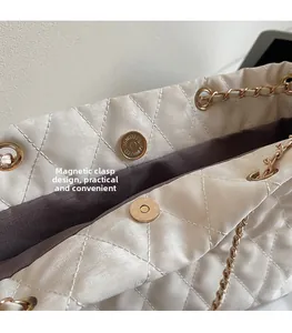 Détail macro du fermoir magnétique doré et de la texture matelassée du sac beige