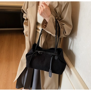 Detail of black suede tote bag with decorative buckle and long leather shoulder straps
