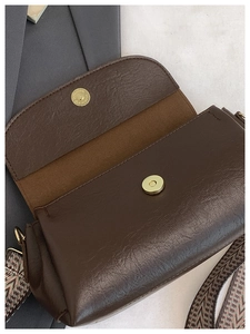 Dettaglio borsa in pelle marrone scuro con chiusura magnetica e tracolla a spina