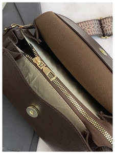 Dettaglio interno della borsa vintage in pelle marrone con tracolla intrecciata e oro