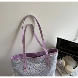 Top view of purple geometric pattern tote bag with laptop, headphones and art book