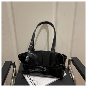 Close-up of gloss black leather tote bag with buckle details and polished finish